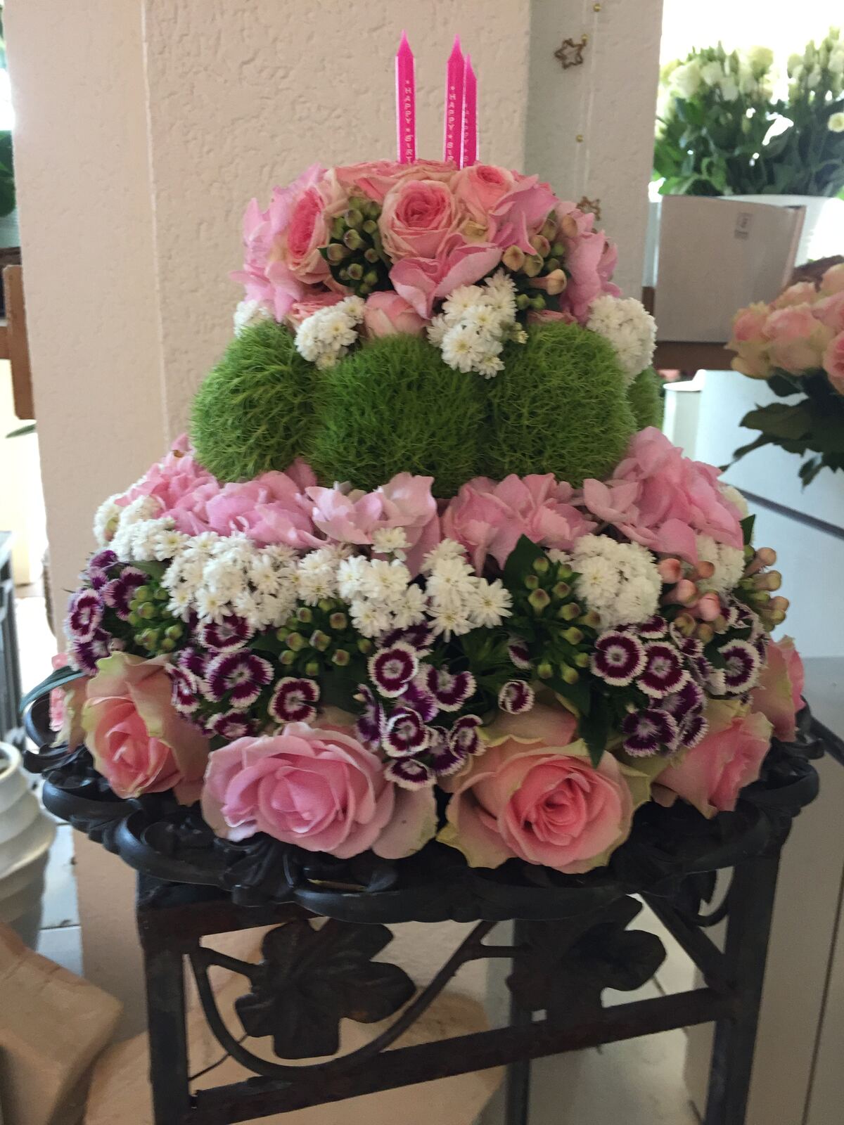 Blumentorte aus rosa Rosen, weißen Blüten und grünen Dianthus-Kugeln